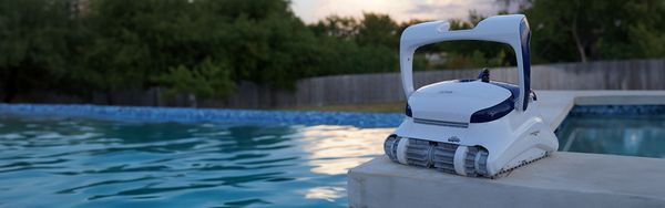 Robotic pool cleaner perched on the edge of a sparkling pool
