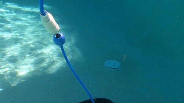 Dolphin E30 with swivel cord climbing from the pool floor toward the tile