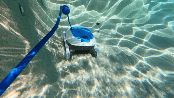 Dolphin Proteus DX3 cleaning along the back wall of the pool