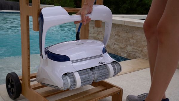 A PoolPad tester carrying a robotic pool cleaner to a real backyard pool