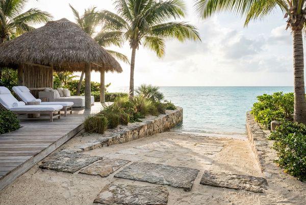 Resort-style beach entry pool with a wide shelf, cabana and lush planting