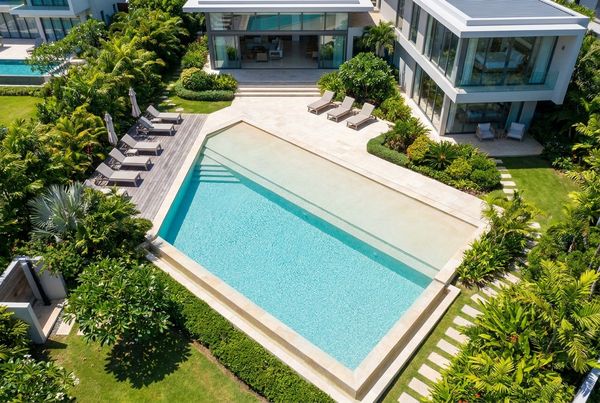 Beach entry pool ringed by tropical planting and loungers