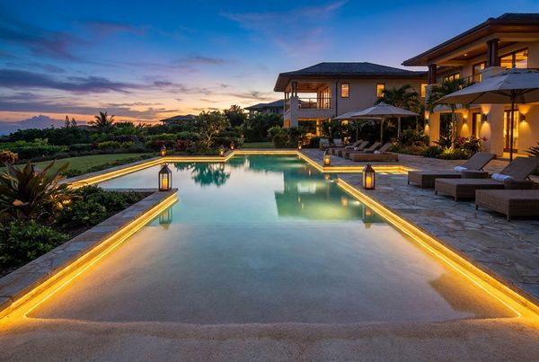 Beach entry pool lit at dusk with glowing shallow shelf