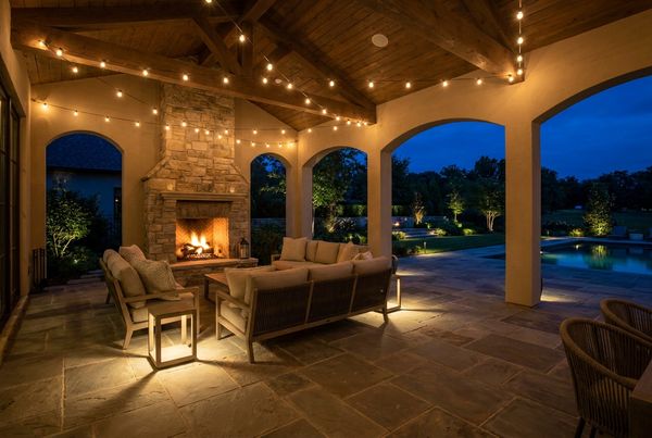 Covered patio glowing with warm lights at night beside a pool