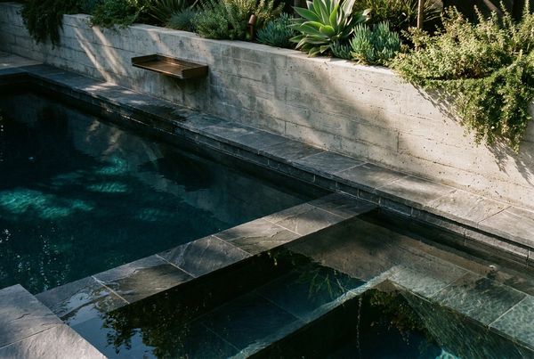 Dark bottom pool with a raised spa spillover
