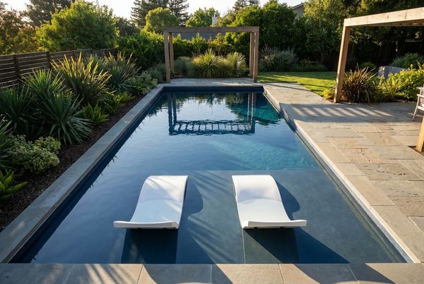 Fiberglass pool with a wide molded tanning ledge and in-water loungers