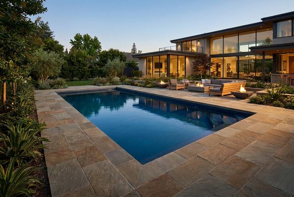 Fiberglass pool bordered by a wide paver deck and lounge seating