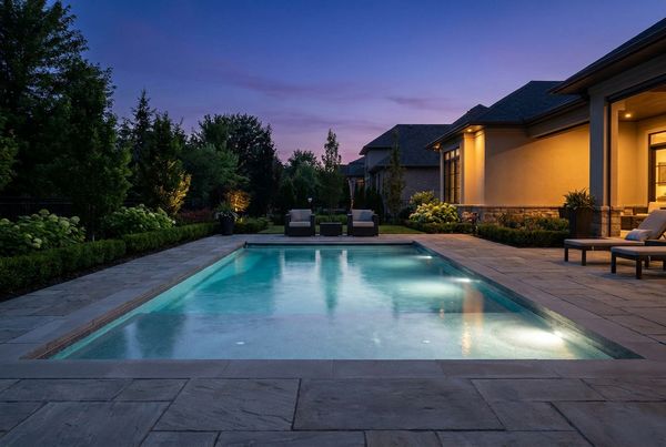 Fiberglass pool with a lit tanning ledge glowing at night