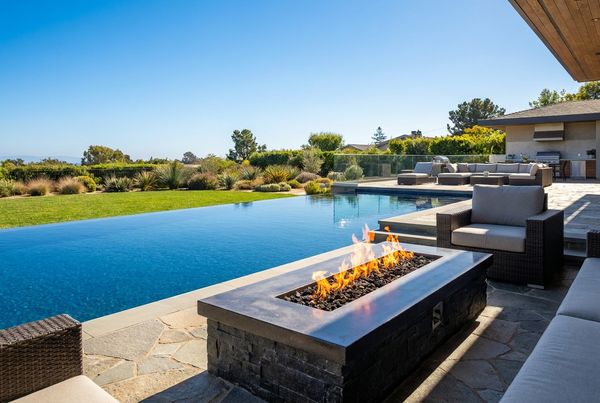 Fire bowls flanking pool steps with flames mirrored in the water