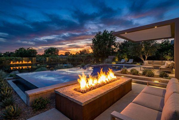 Raised pool wall topped with matching fire bowls at night