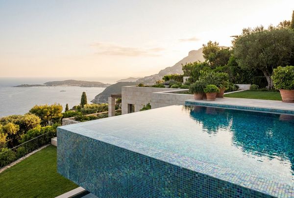Glass tile infinity edge pool spilling toward a view