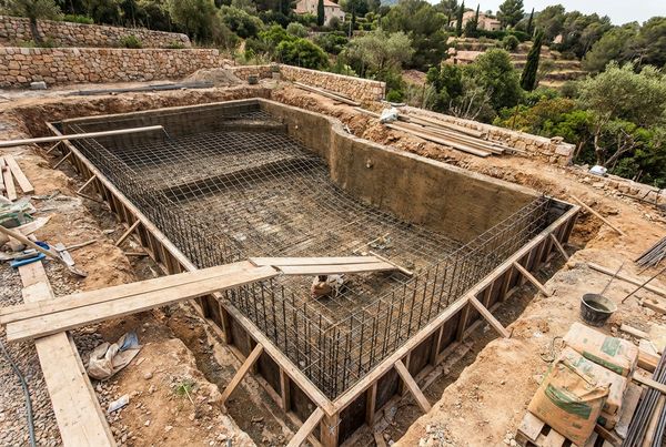 Gunite pool shell under construction showing steel rebar and sprayed concrete