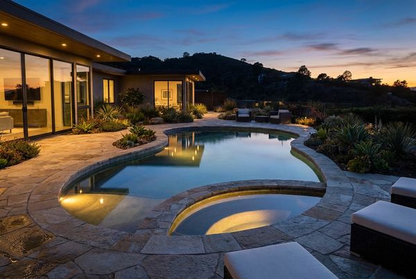 Custom gunite pool lit in blue and warm light at dusk