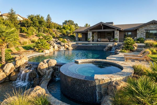 High-end inground pool with a spa and waterfalls at dusk