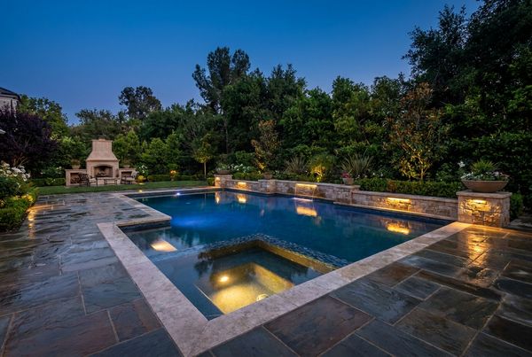 Completed inground pool lit at dusk with landscape lighting