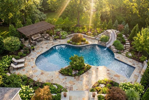 Backyard pool with bubblers erupting on a shallow shelf while kids play