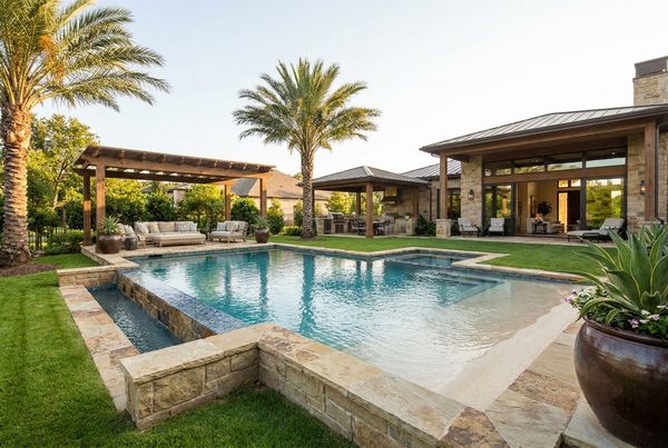 Freeform family pool with a boulder waterfall and shallow lagoon shelf