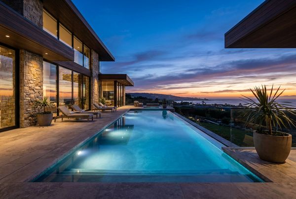 Lap pool lit at dusk with warm lighting reflecting on the water