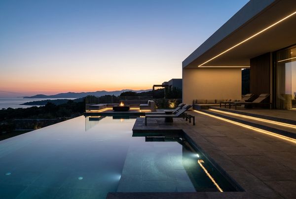 Luxury pool lit at dusk with fire bowls and a glowing spa