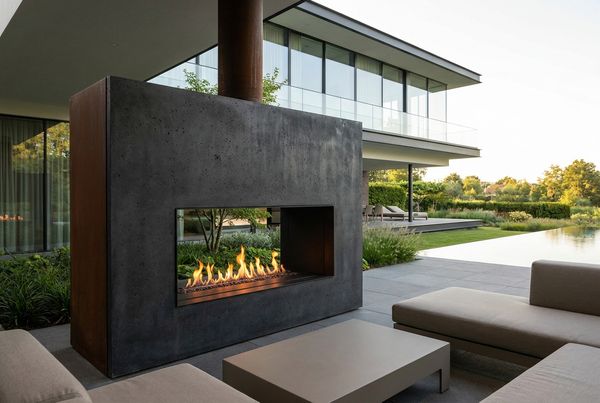 Rustic brick outdoor fireplace with stacked firewood nearby