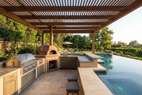 L-shaped outdoor kitchen with a built-in grill and pizza oven under a covered patio