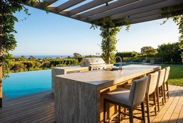 Outdoor kitchen island with bar seating and stools facing the pool