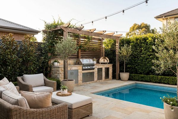 Poolside straight-run outdoor kitchen against a garden wall