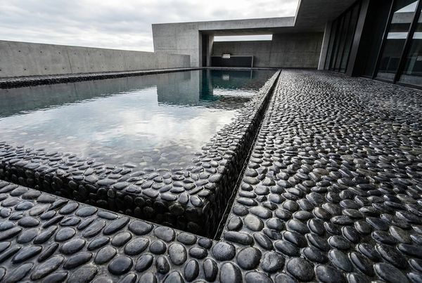 Modern pool with a dark reflective pebble finish mirroring the sky