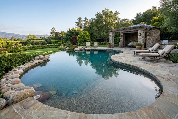 Freeform pebble finish pool set into a landscaped backyard