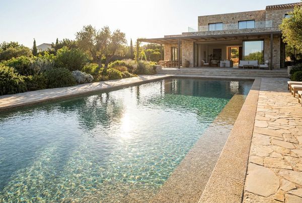 Sunlit pebble pool with sparkling clear water and a clean deck
