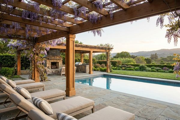 Cedar wood pergola covered in blooming wisteria over a stone patio