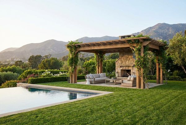 Freestanding pergola on a lawn beside a pool deck