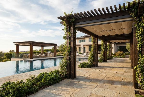 Attached pergola shading a paved patio beside a pool