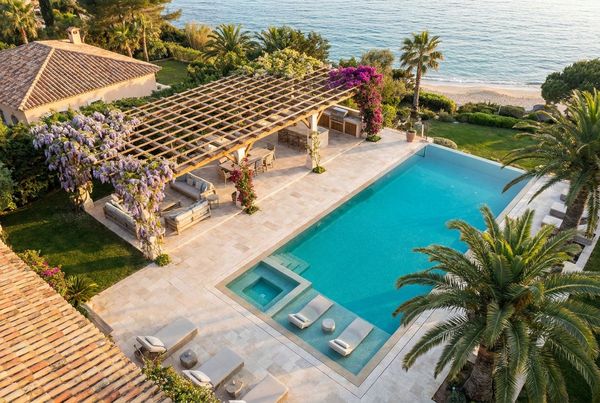 Black aluminum louvered pergola open to the sky over a pool patio