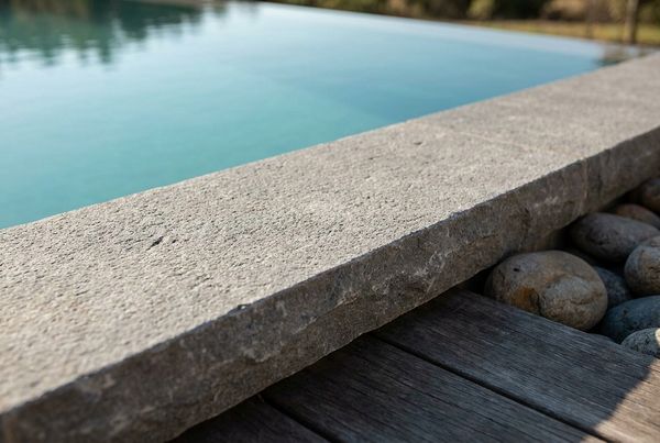 Close-up of a bullnose travertine coping edge at the pool waterline