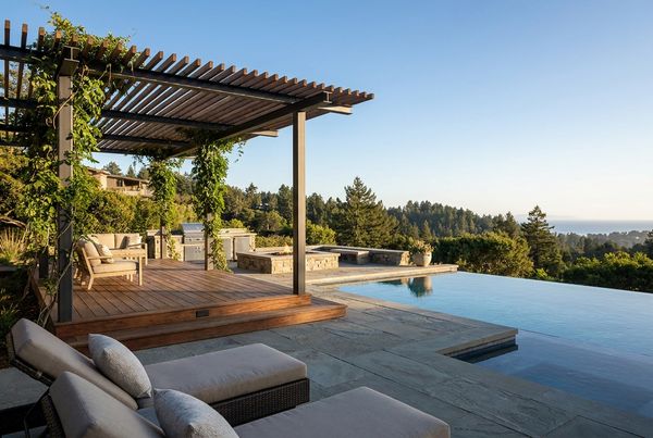 Pool deck shaded by a modern pergola with lounge seating