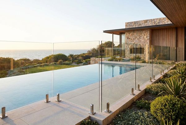 Glass-panel pool fence framing a modern backyard pool