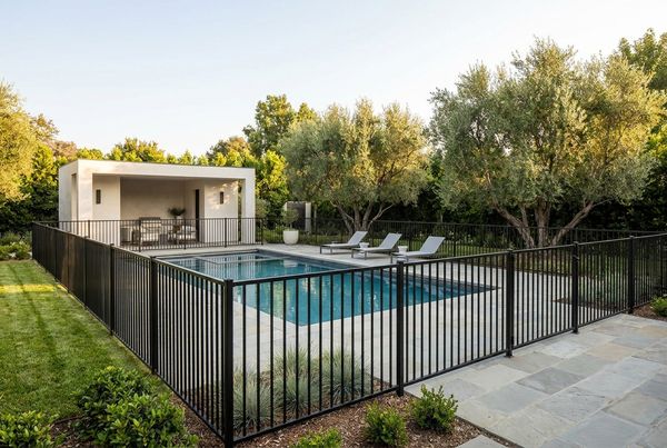 Black aluminum pool fence running along a paved pool deck