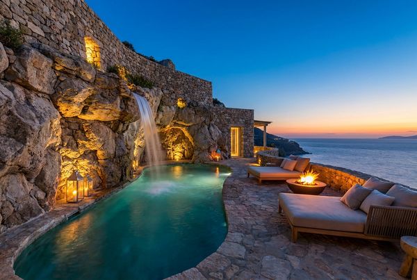 Pool grotto lit at dusk showing the scale of the rockwork and waterfall