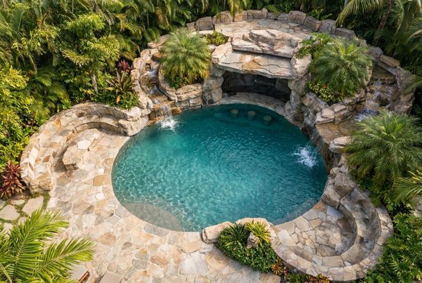 Pool grotto lit in warm light at night with a glowing waterfall