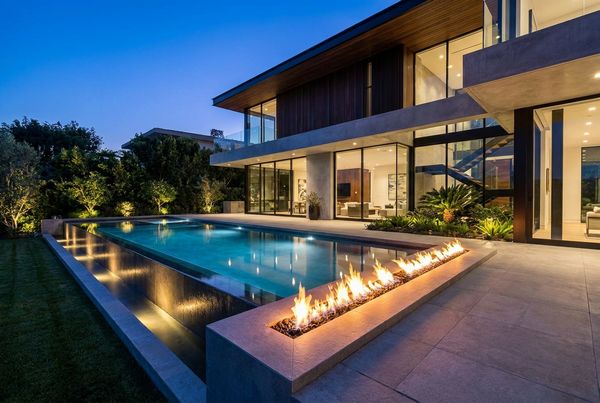 Modernized pool with an integrated fire feature glowing at dusk