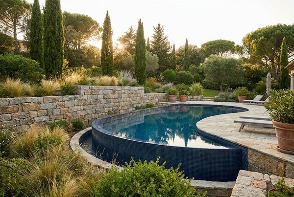 Natural stone retaining wall wrapping a poolside terrace