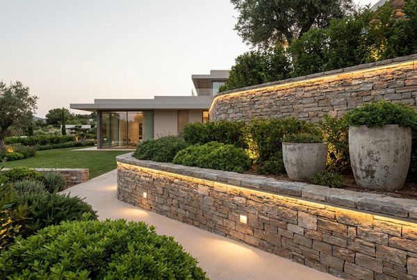 Retaining wall with integrated lighting glowing warmly beside a pool at night