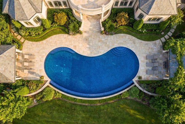 Aerial view of a kidney-shaped pool with a curved deck