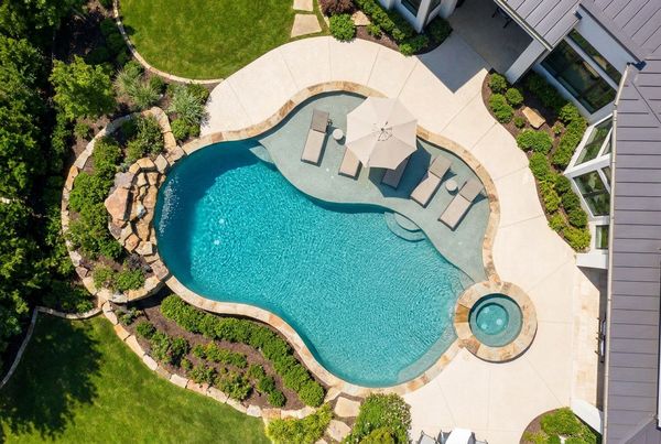 Aerial view of a pool with a large sun shelf and lounge chairs