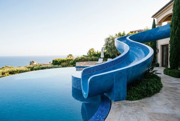 Curved blue pool slide winding into a backyard pool