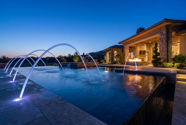 Glowing laminar deck jets arcing over a pool at night