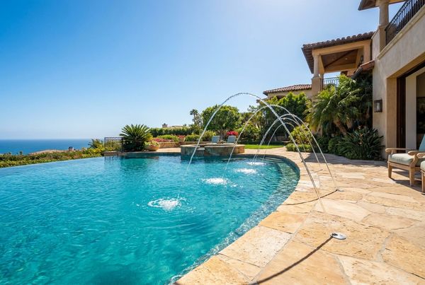 Deck jets arcing over a pool in daylight