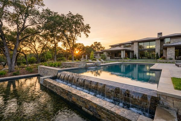 Sheer-descent waterfall wall pouring into a modern pool