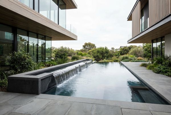 Water wall with mosaic glass tile behind a pool
